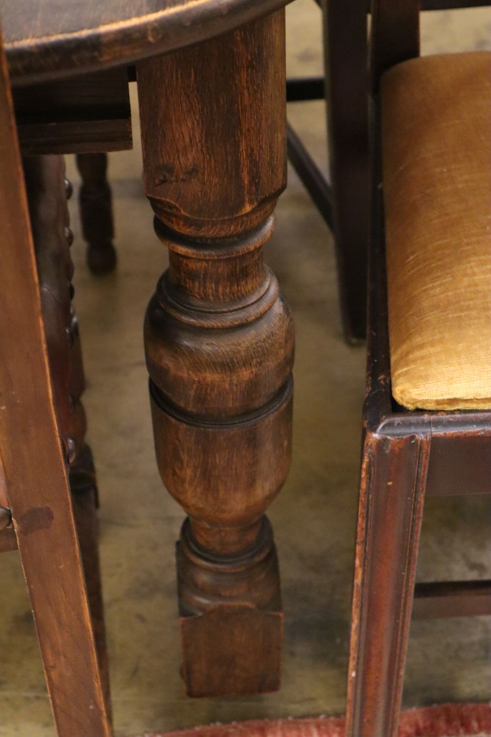 A 1930s oak extending dining table 234cm extended (two spare leaves) and seven dining chairs (one with arms)